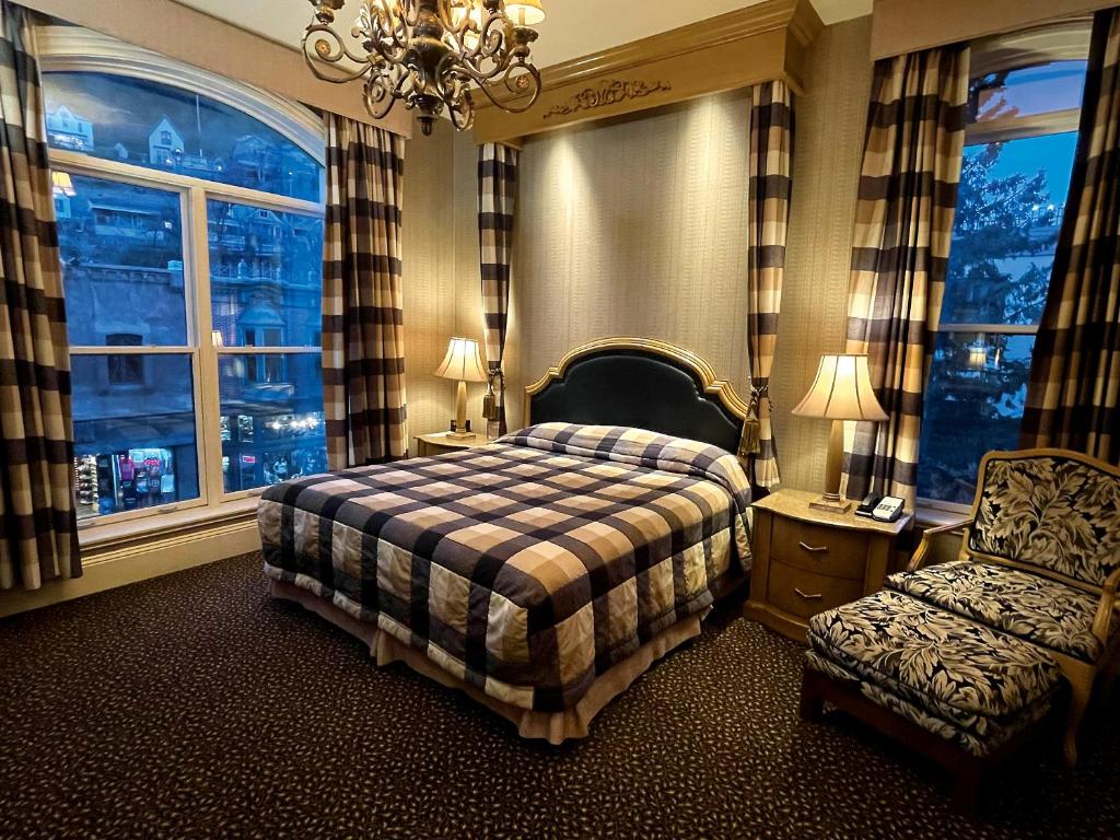a bedroom with a bed and a chair and windows at Celebrity Hotel in Deadwood