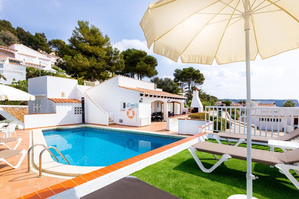 a villa with a swimming pool and an umbrella at Villa Es Mirador in Son Bou