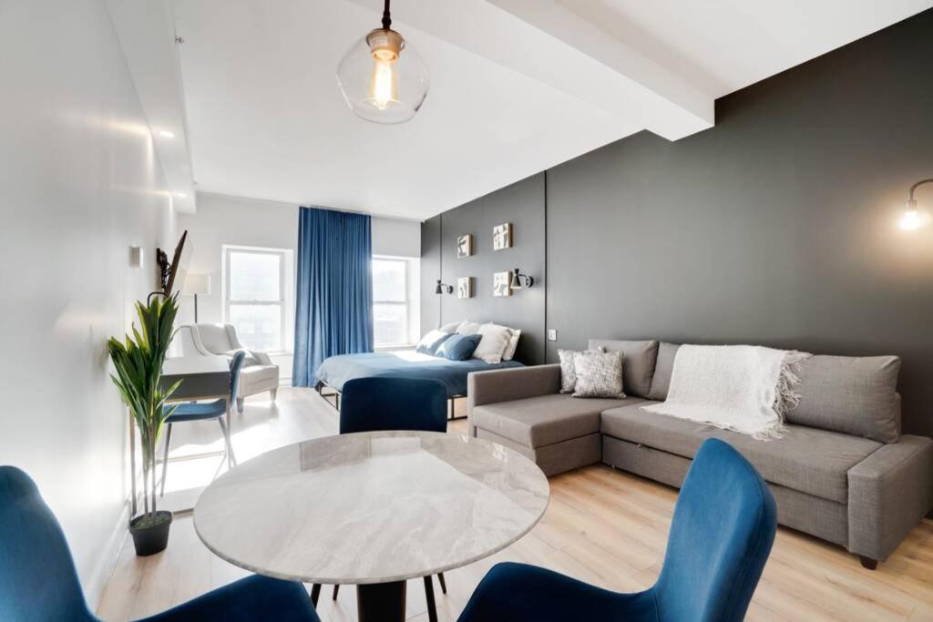 Una sala de estar con un sofá, una mesa y sillas. en INITIAL - SUITE LUMIÈRE - Centre-Ville de Québec, en Quebec