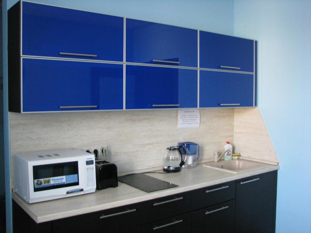 a kitchen with blue cabinets and a sink and a microwave at Parus Hotel in Korolyov