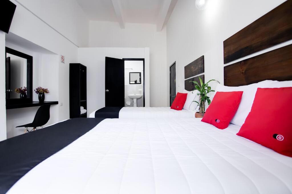 um quarto com uma grande cama branca com almofadas vermelhas em Hotel Pósada Maria Isabel em Atlixco