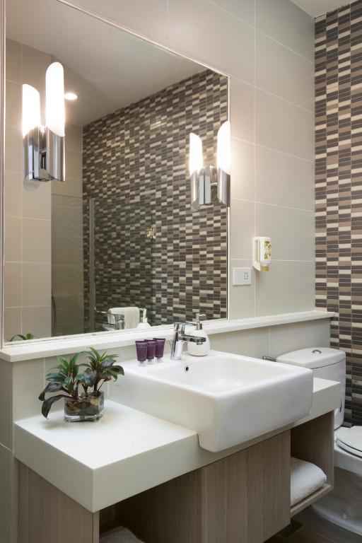 Un baño con lavabo, espejo e inodoro. en Citadines Uplands Kuching, en Kuching