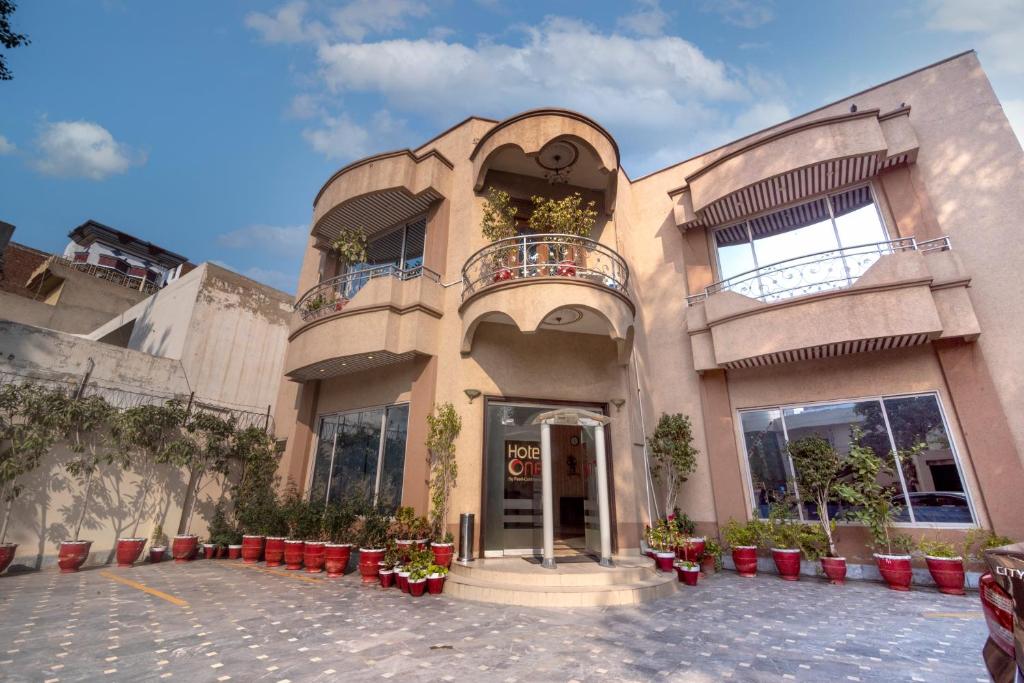 a building with plants in pots in front of it at Hotel One Lalazar Multan in Multan