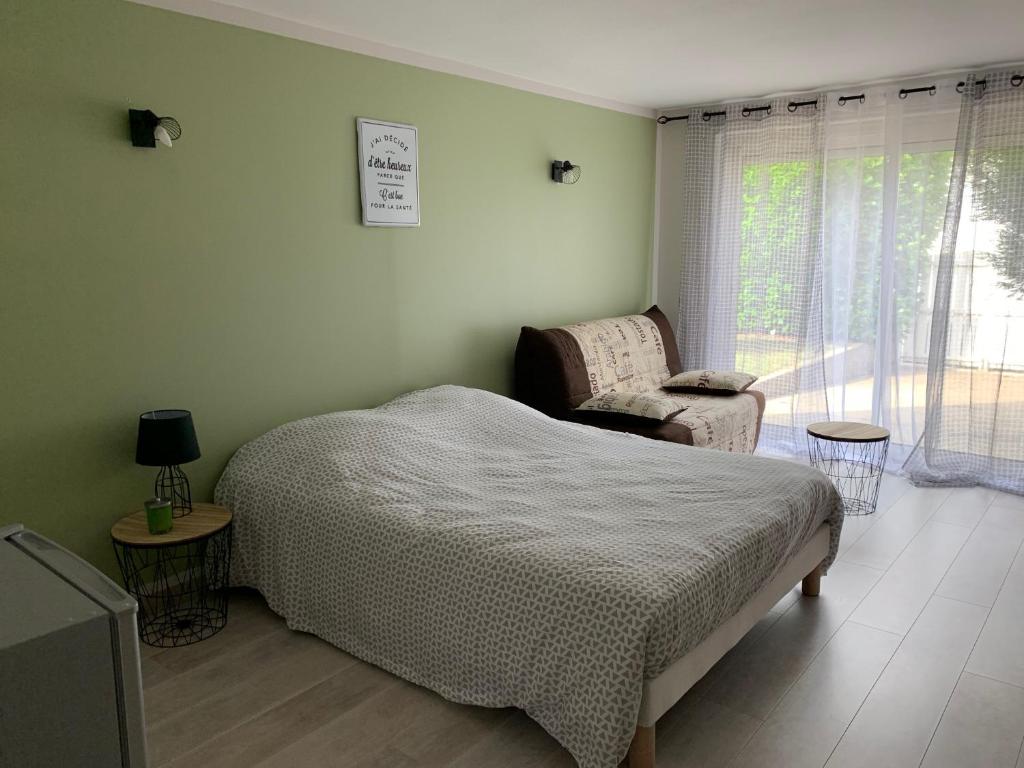 1 dormitorio con 1 cama, 1 silla y 1 ventana en Chambre aux portes du marais Poitevin, en Aiffres