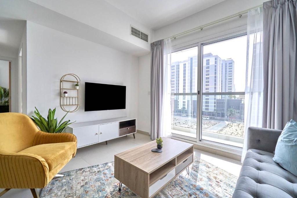 a living room with a couch and a tv and a large window at Stella Stays Chic 2 BDR Dubai JVC Large Terrace in Dubai