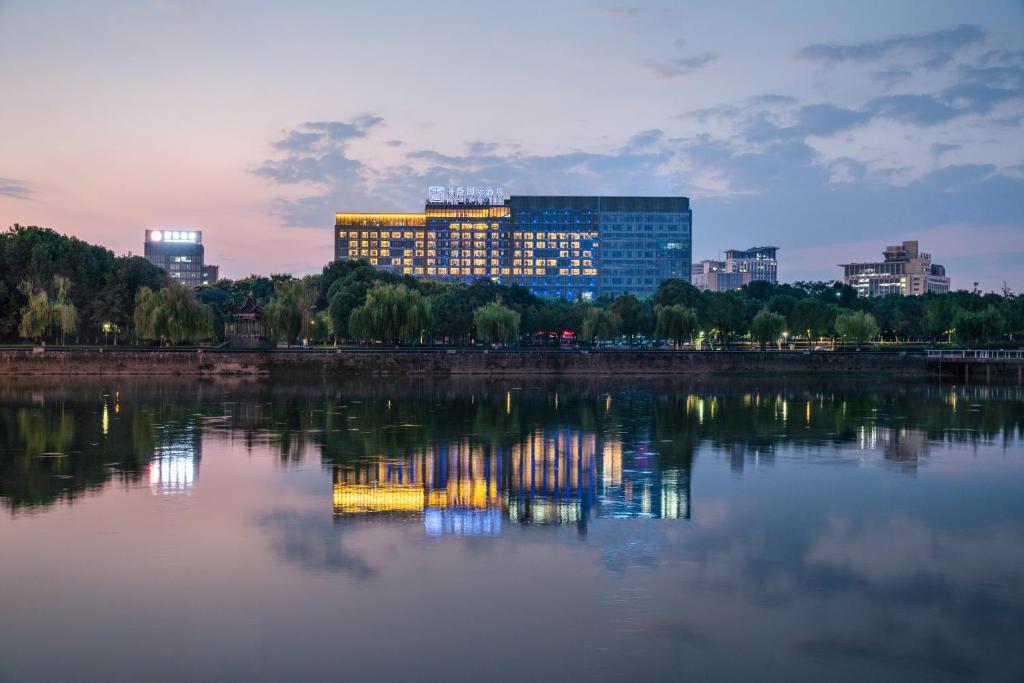 eine Skyline der Stadt mit einem großen Gebäude auf dem Wasser in der Unterkunft Kasion International Hotel Yiwu in Yiwu