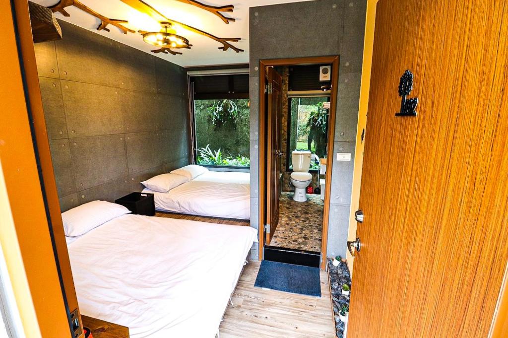 a room with two beds and a bathroom with a toilet at Carefree Park in Taichung