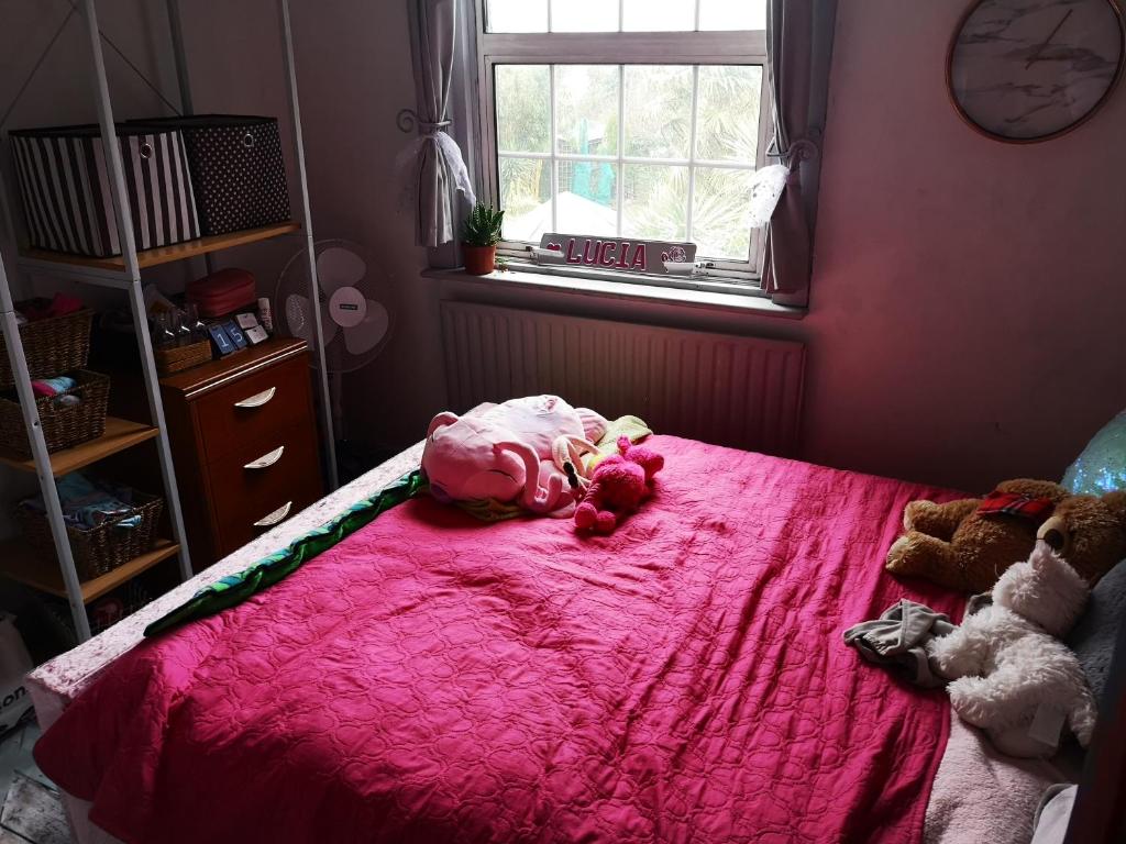 a bedroom with a pink bed with stuffed animals on it at English Riviera Coves and Beaches in Dartmouth