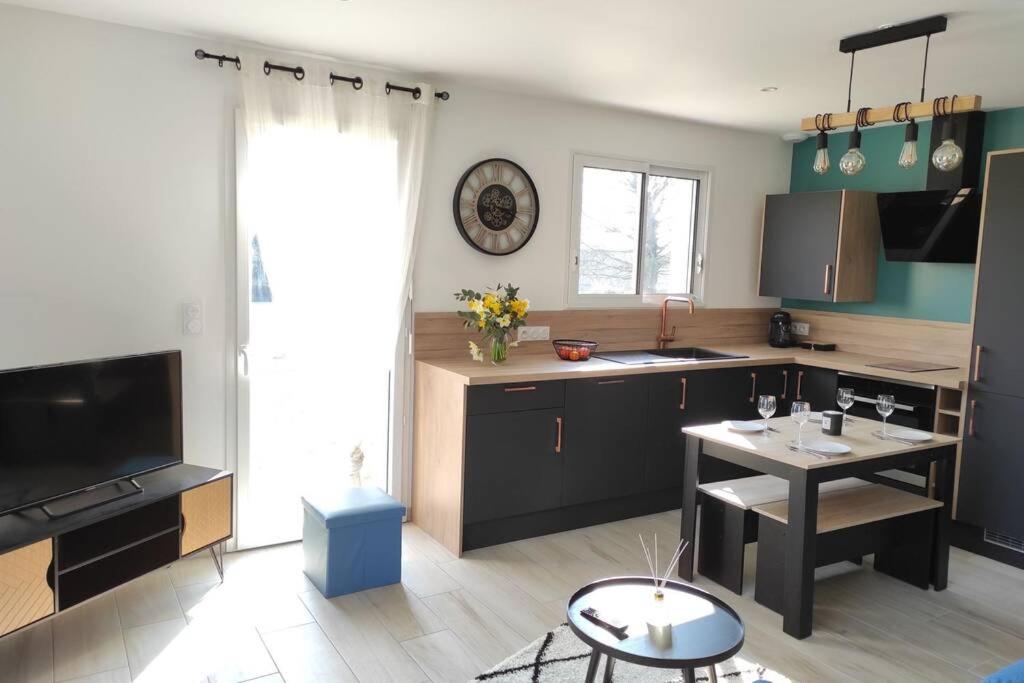 eine Küche mit einem Tisch und einem großen Fenster in der Unterkunft Au bonheur des Landes Logement neuf tout confort proche forêt et ville in Colombiers