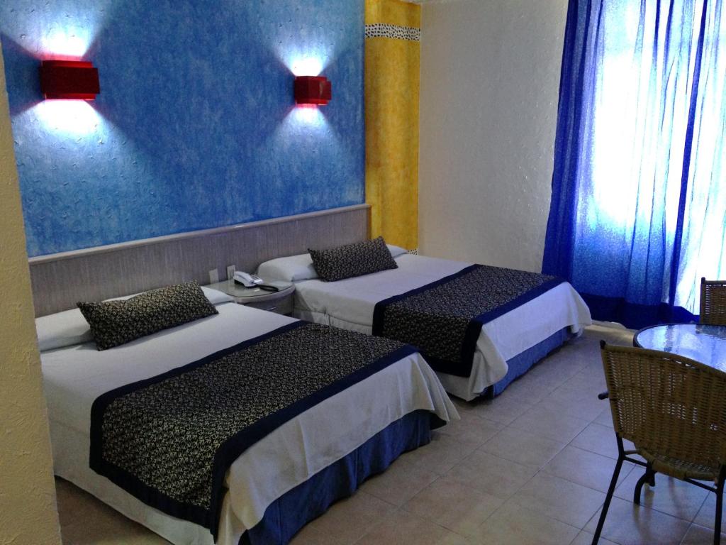 Habitación de hotel con 2 camas y mesa en Hotel Club del Sol Acapulco by NG Hoteles en Acapulco