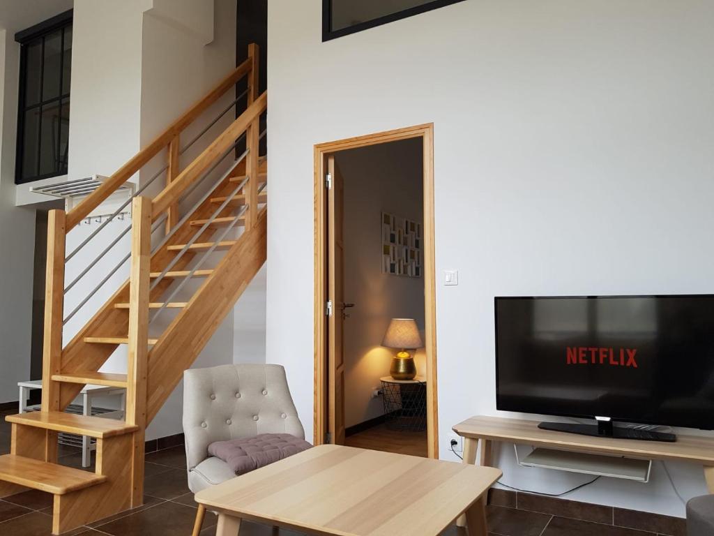 un salon avec une télévision et un escalier dans l'établissement L'Arbre, au Mans