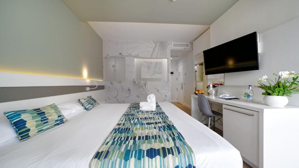 a hotel room with a large white bed and a kitchen at Hotel Aloe Canteras in Las Palmas de Gran Canaria