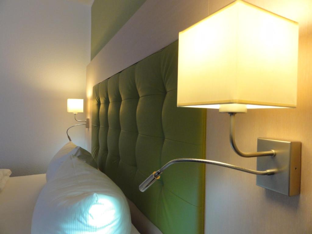 a lamp on a wall next to a bed at Pension Zeitlos in Potsdam