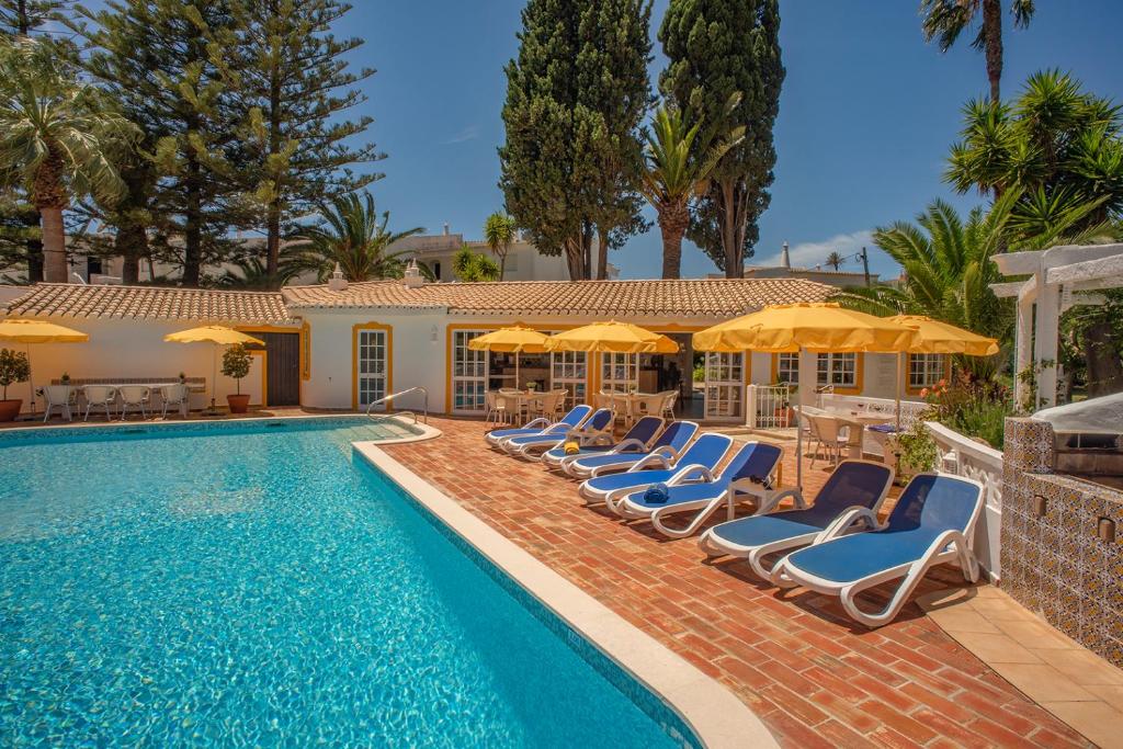 uma piscina com espreguiçadeiras e guarda-sóis em Quinta Paraiso da Mia - Two bedroom apartment na Praia da Luz