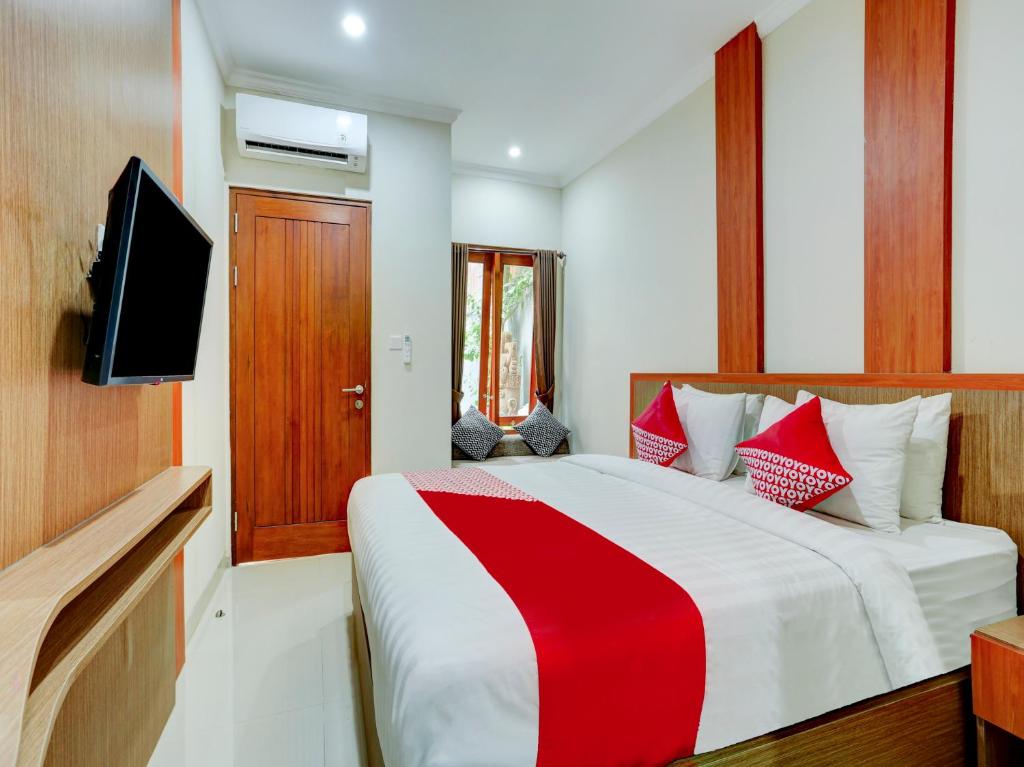 1 dormitorio con 1 cama roja y blanca y TV en Super OYO Capital O 90291 Vin Stay Petanu, en Pesanggaran