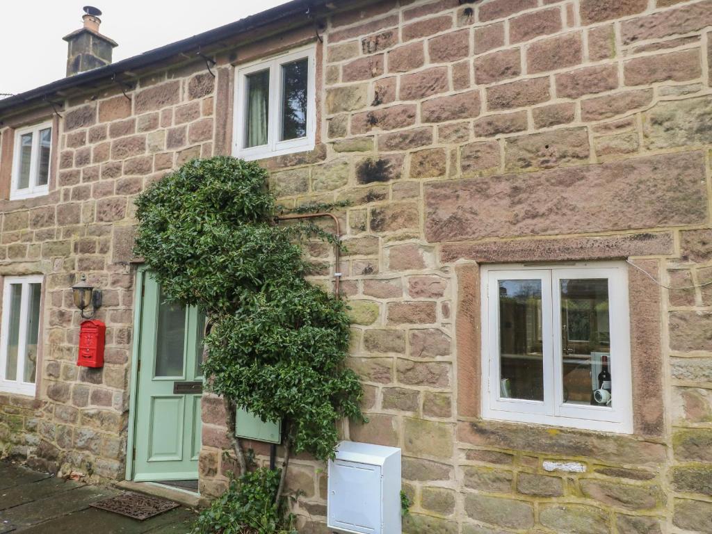 an old stone house with a green door and windows at Croft Cottage in Matlock