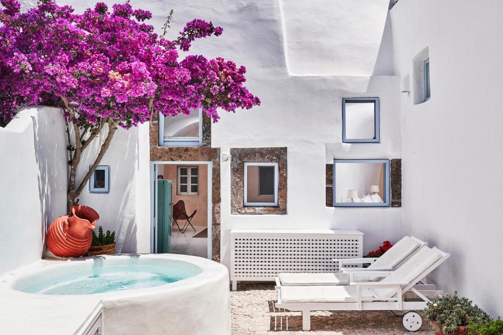 um quarto com uma banheira e uma árvore com flores roxas em 2 bedroom charming villa with outdoors jacuzzi em Megalochori