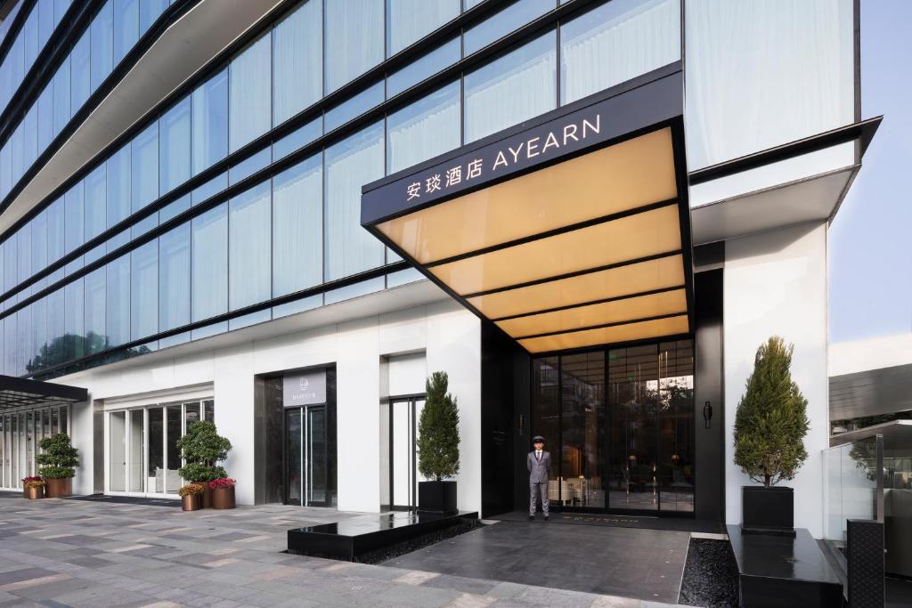 a man stands in front of a building at Shenzhen Ayearn Hotel in Shenzhen