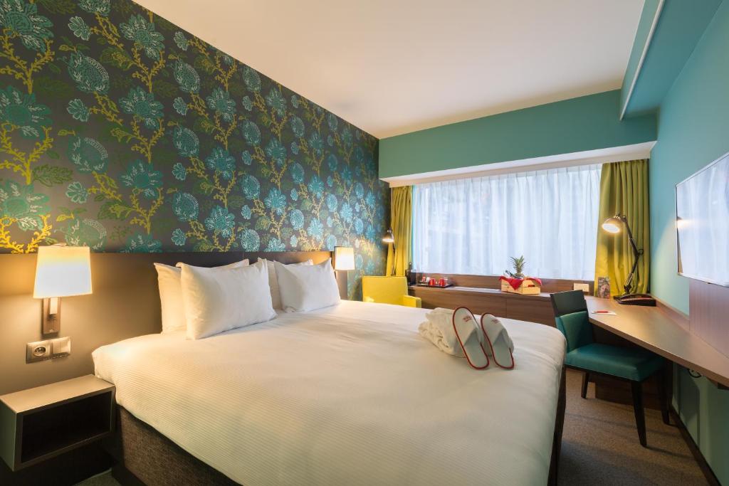Una habitación de hotel con una cama con dos zapatillas. en Thon Hotel Brussels City Centre en Bruselas