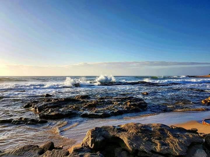 a beach with rocks and waves in the ocean at Holiday unit 37 Eden dunes in Shelly Beach