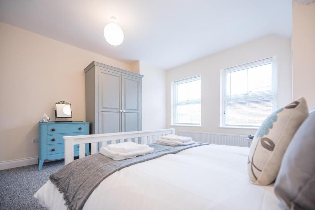 sypialnia z białym łóżkiem i niebieską komodą w obiekcie 2 Abbey Mews, Leiston w mieście Leiston