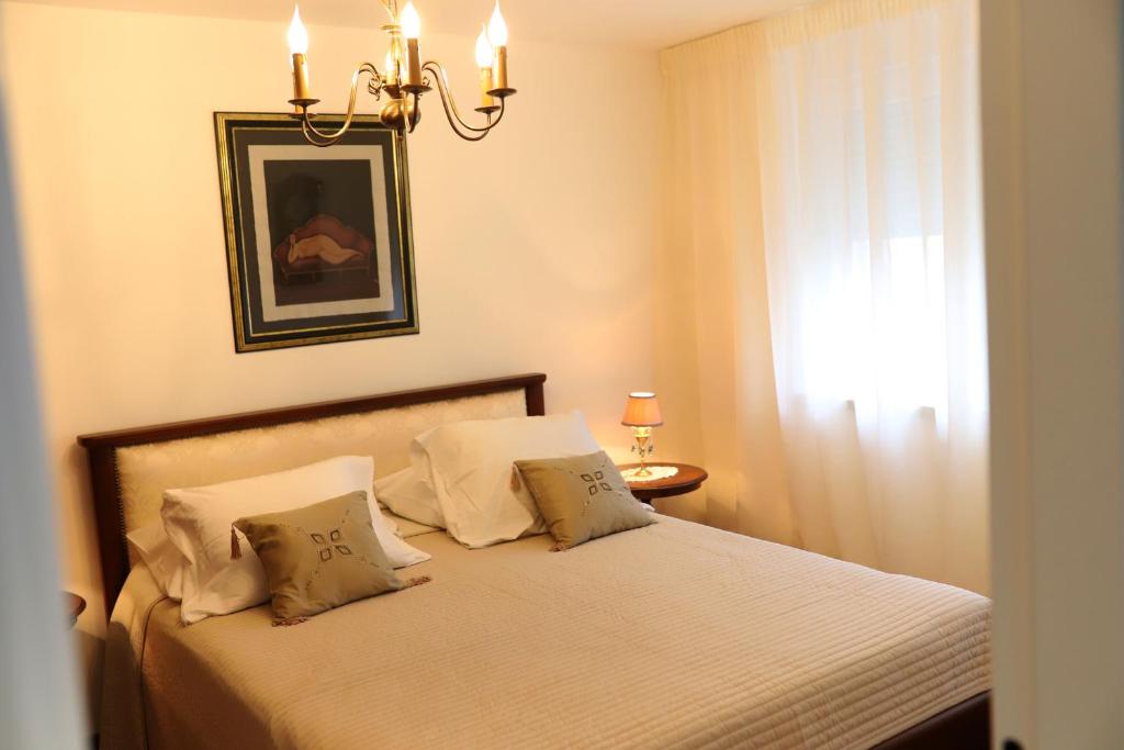 a bedroom with a bed with a chandelier and a window at Apartment Blaoss in Karlovac