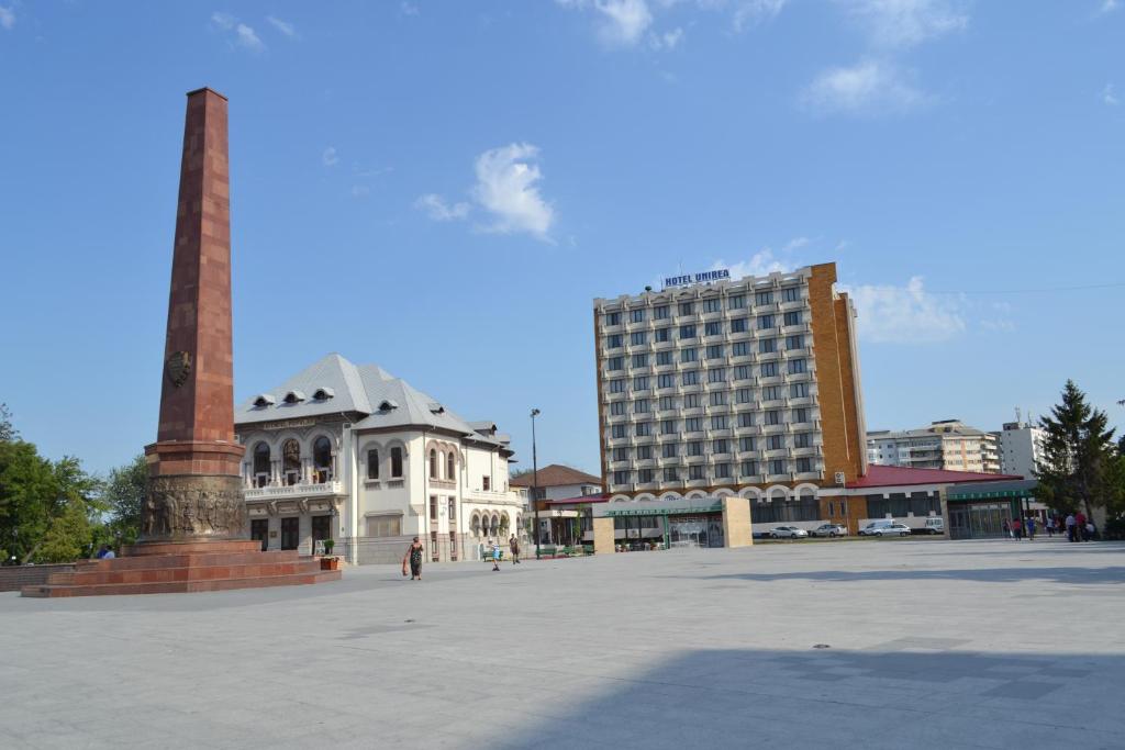 ein Stadtplatz mit einem hohen Gebäude und einem Denkmal in der Unterkunft Hotel Unirea in Focşani
