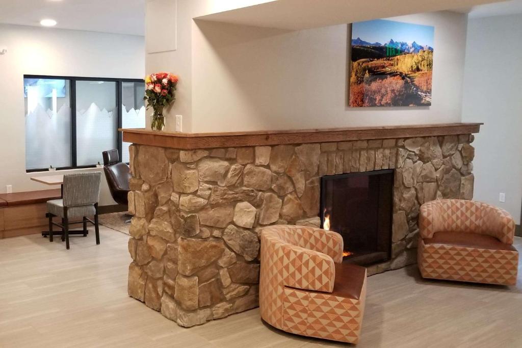 una chimenea de piedra en una sala de estar con sillas y mesa. en Microtel Inn & Suites by Wyndham Georgetown Lake en Georgetown