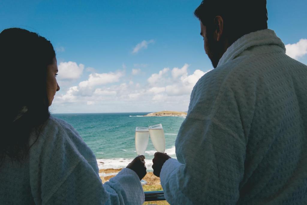 a man and a woman holding champagne glasses overlooking the ocean at Fistral Beach Hotel and Spa - Adults Only in Newquay