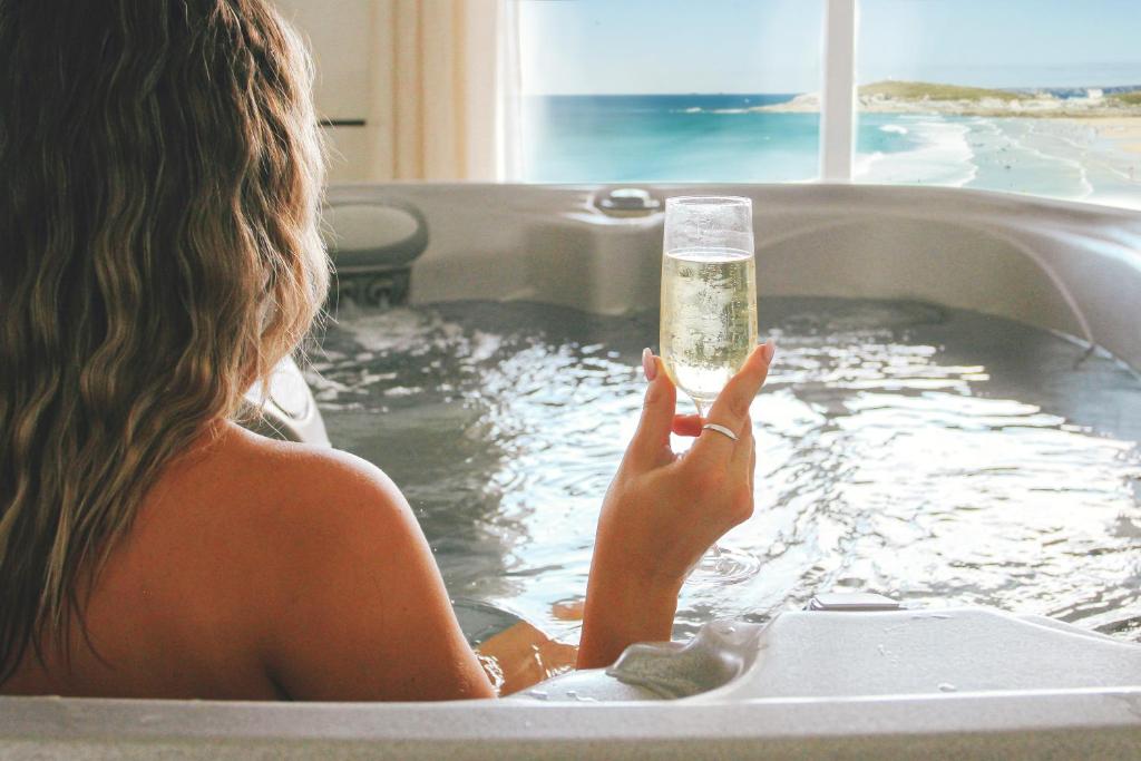 a woman in a bathtub holding a glass of water at Fistral Beach Hotel and Spa - Adults Only in Newquay