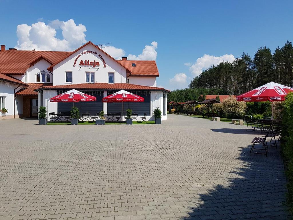 un edificio con sombrillas rojas en un patio en Centrum Turystyki Wiejskiej Alicja, en Księżpol