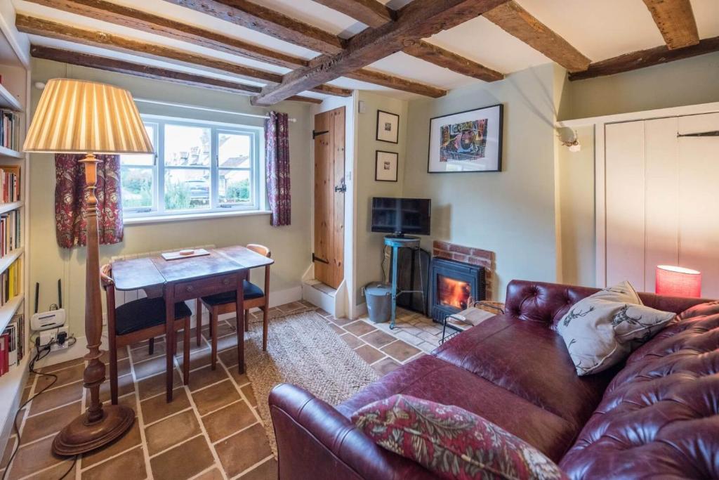 een woonkamer met een bank, een tafel en een open haard bij Library Cottage, Marlesford in Woodbridge