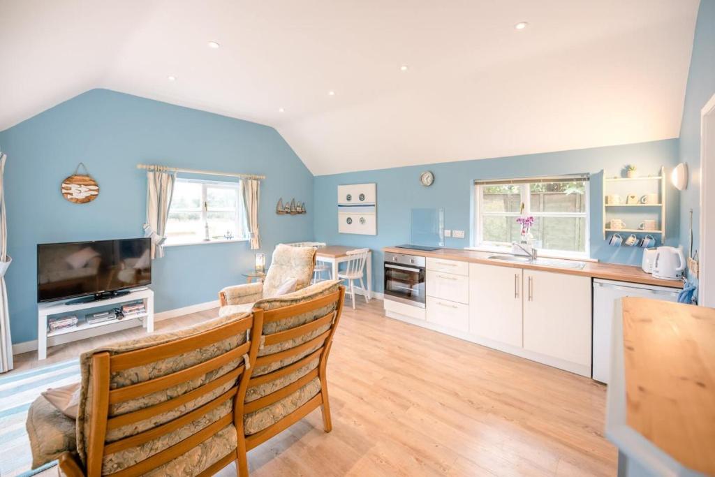 a kitchen with blue walls and white cabinets and a table at Little House, Aldringham in Leiston