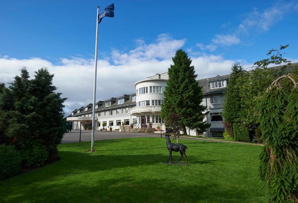 a statue of a giraffe in the grass in front of a building at Macdonald Drumossie Hotel Inverness in Inverness