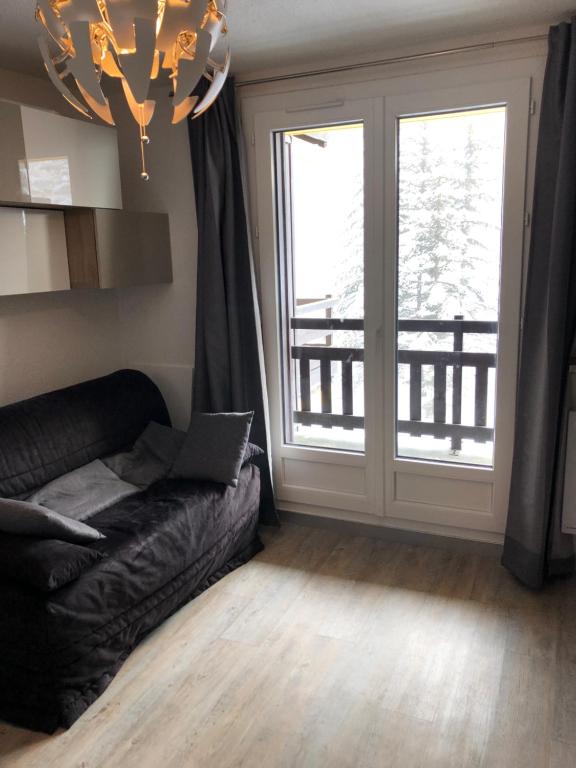 a living room with a couch and a large window at Boost Your Immo Les Clarines Risoul 451 in Risoul