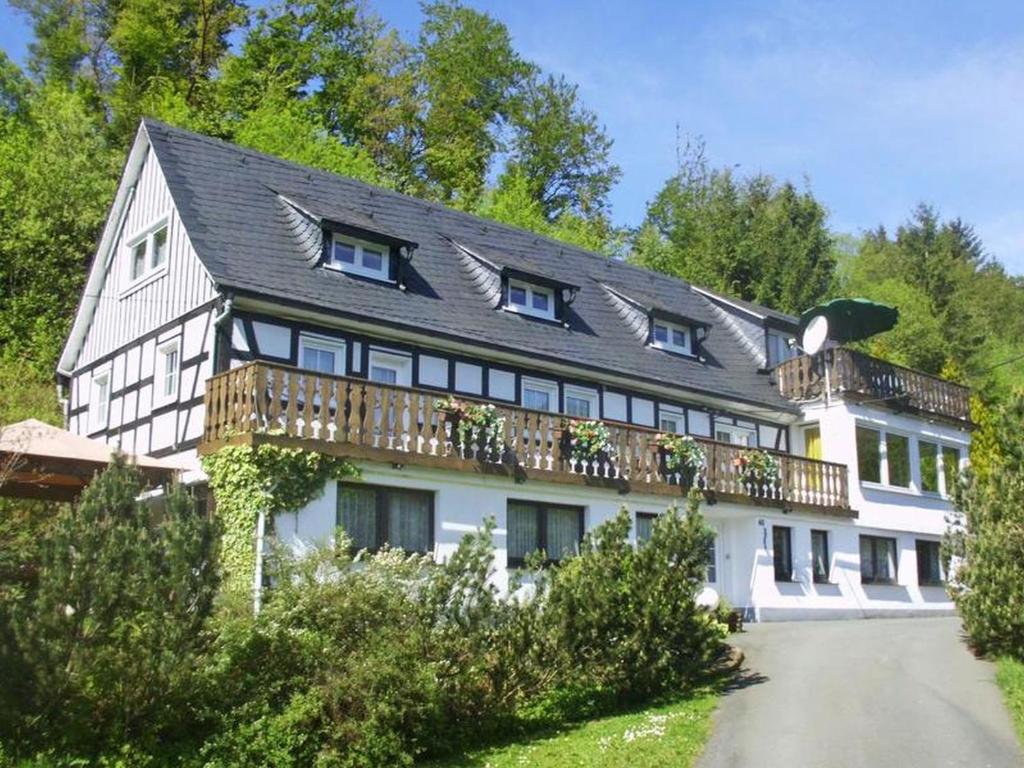 a white house with a black roof and a balcony at Ferienwohnungen Demberg in Schmallenberg