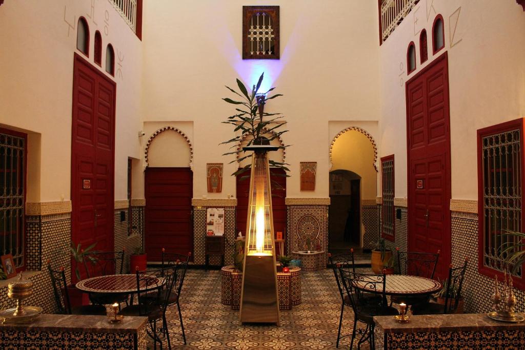 a room with tables and chairs and a fountain in a building at Riad Meftaha in Rabat