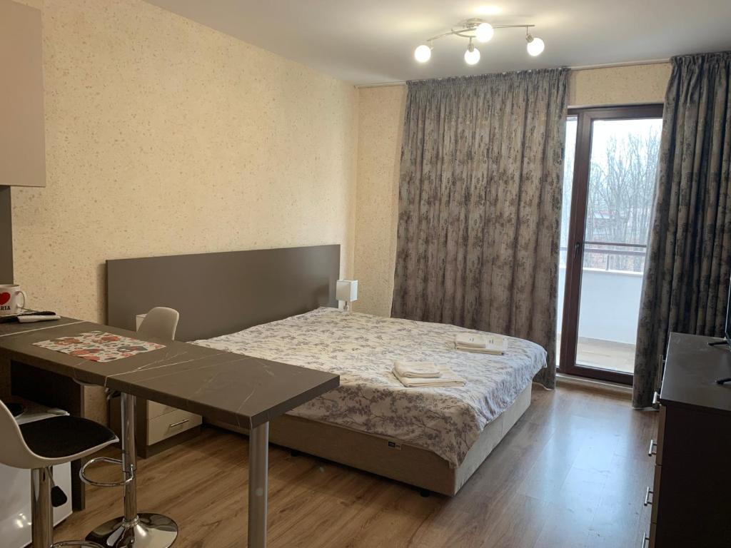 1 dormitorio con cama, mesa y ventana en Студио Кати, en Shkorpilovtsi