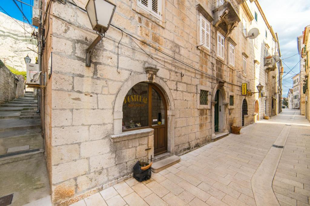 an alley with a building with a window and a cat sitting outside at Apartment Kalalarga in Makarska