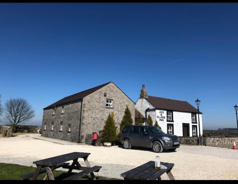 a car parked in front of a building with a bench at The Jug & Glass Inn in Hartington