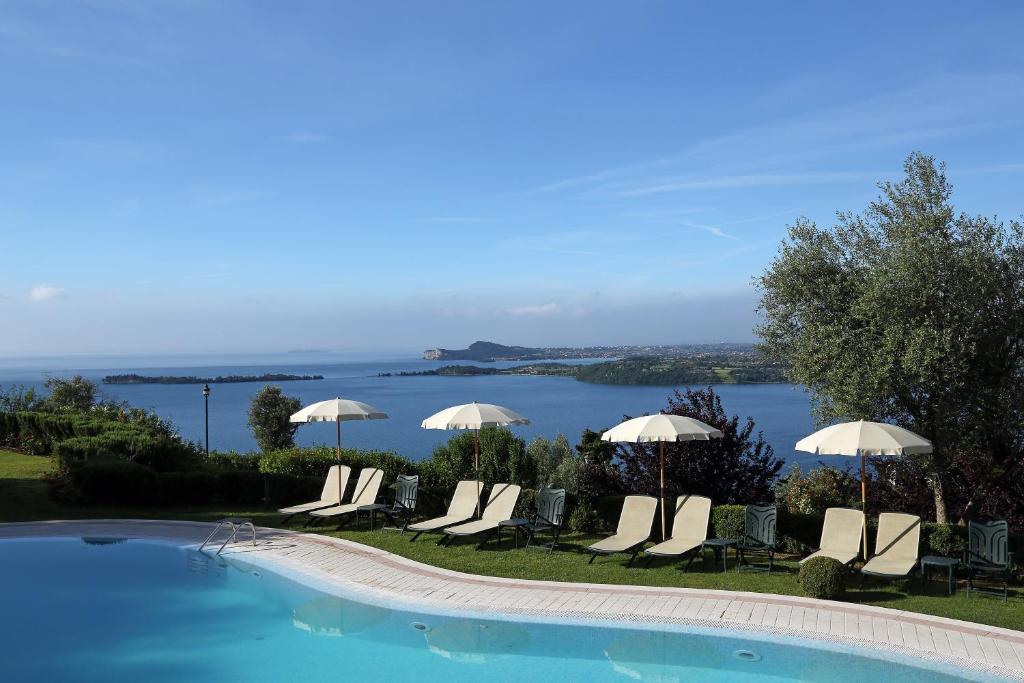 a group of chairs and umbrellas next to a swimming pool at Appartamenti Borgo in Gardone Riviera