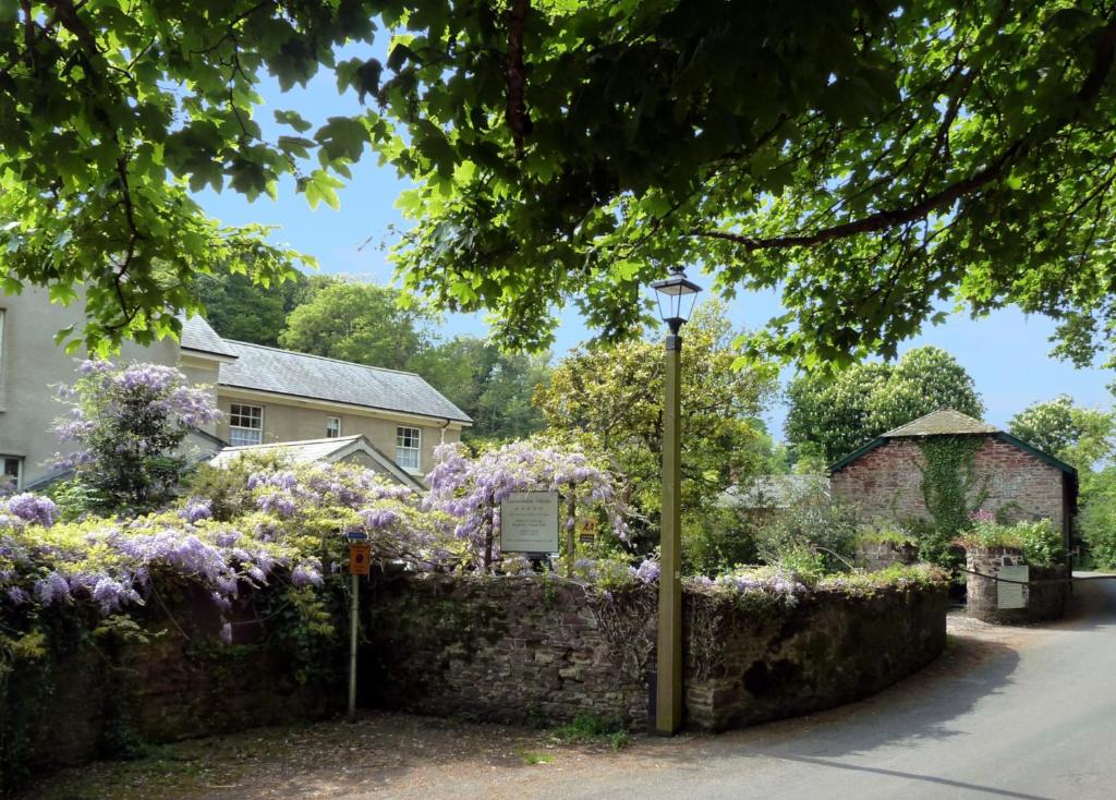 un jardín con flores púrpuras y luz de la calle en Cockington Cottages en Torquay