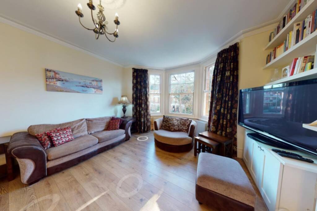 a living room with a couch and a flat screen tv at Superb 2 bedroom flat w garden - 1 min to Queen's Park in London