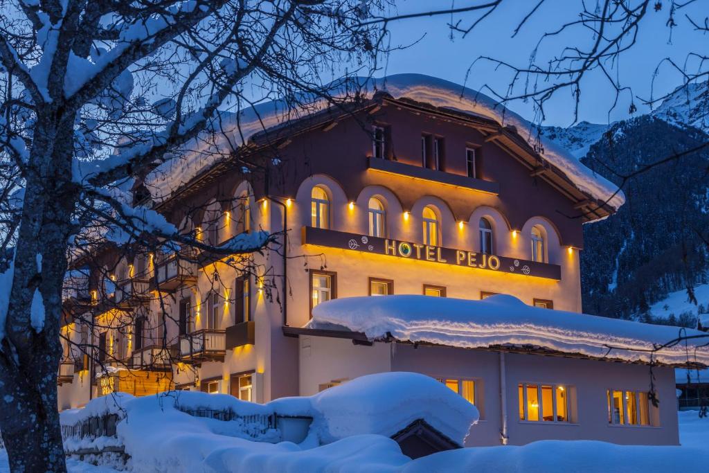 ペーイオ・フォンティにあるHotel Pejoのホテルは雪の中で照らされています