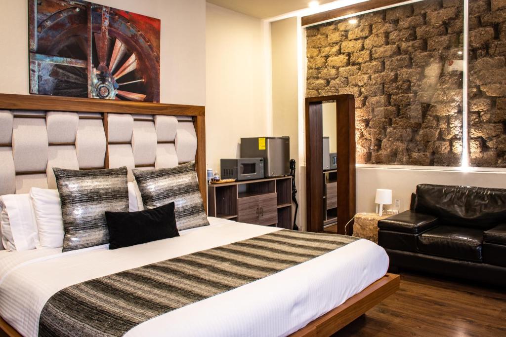 - une chambre avec un grand lit et un fauteuil en cuir noir dans l'établissement Hoteles ANTIGUA - SANTA LUCIA MTY, à Monterrey