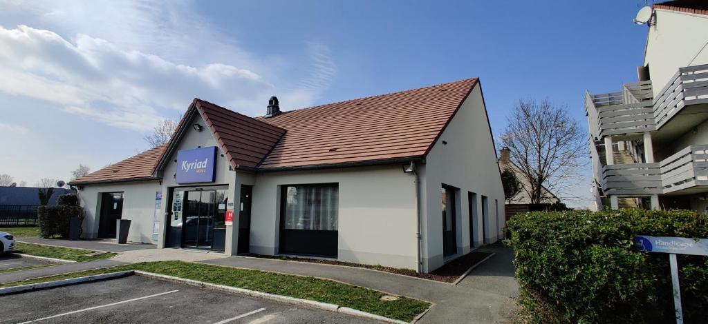 a white building with a brown roof on a street at Kyriad Fontenay - Trésigny in Fontenay-Trésigny
