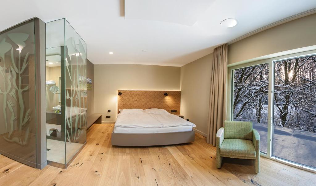 Hotel Weiherhof am Golfpark في فاديرن: غرفة نوم مع سرير ودش زجاجي