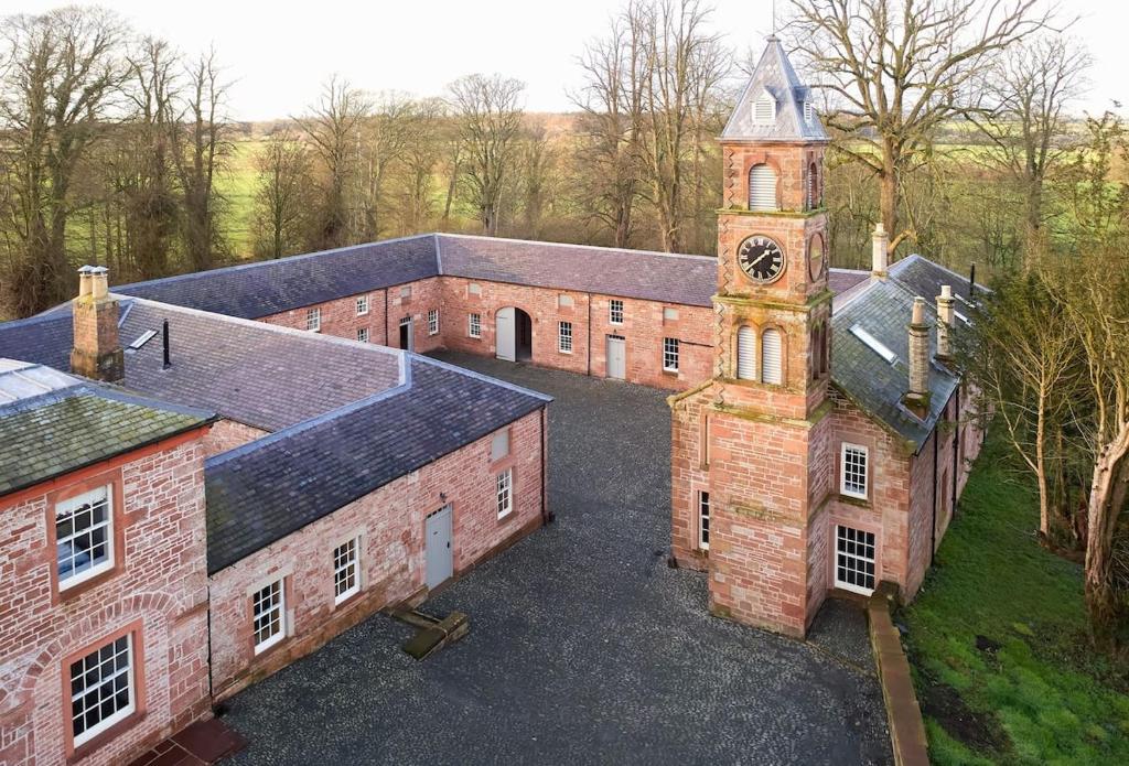 una vista aerea di un vecchio edificio in mattoni con torre dell'orologio di Netherby Hall a Carlisle