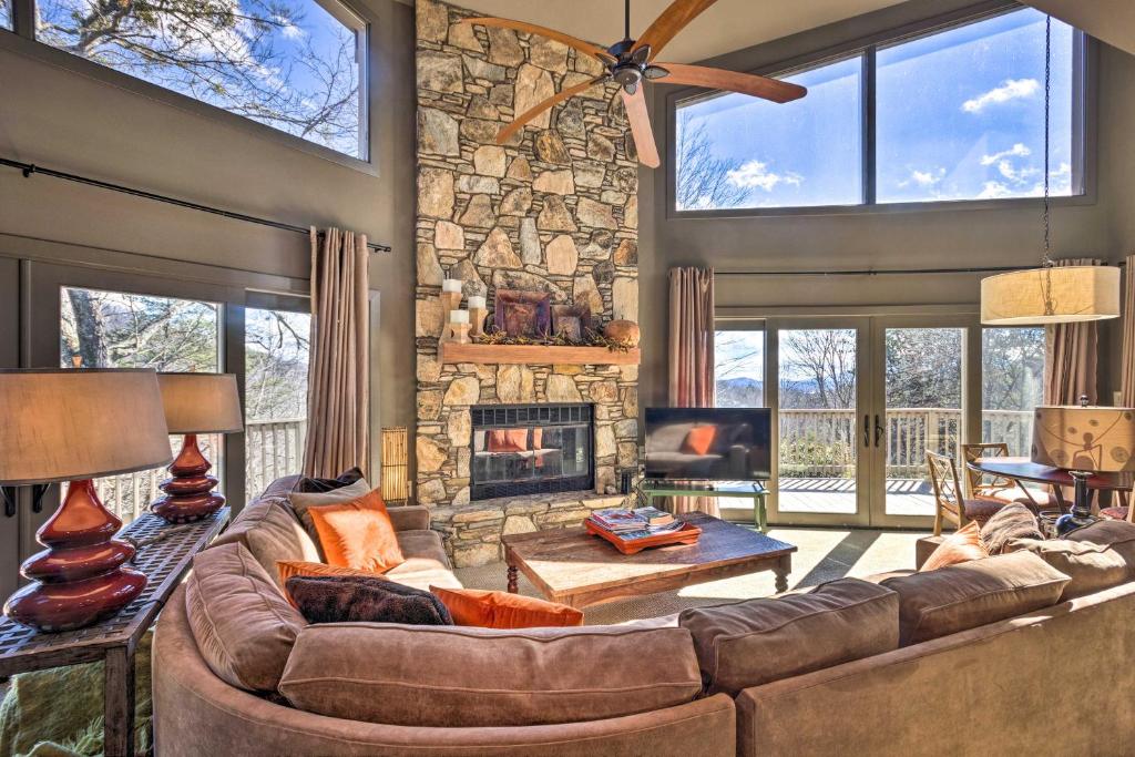 een woonkamer met een bank en een stenen open haard bij Luxe Rumbling Bald Retreat with Deck and Mountain View in Lake Lure