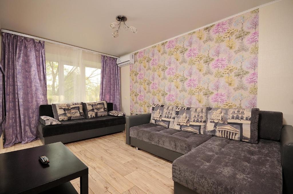 a living room with couches and a floral wall at Omsk Sutki Apartments at 4th Poselkovaya 44 in Omsk